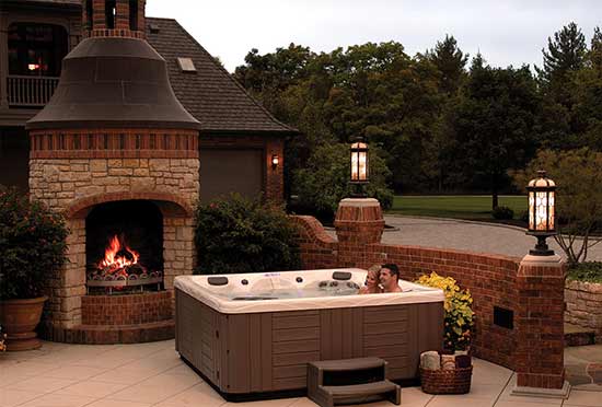 Outdoor hot tub on patio with fireplace