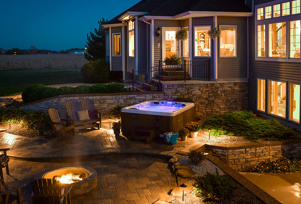 Hot tub on paver patio with firepit in evening